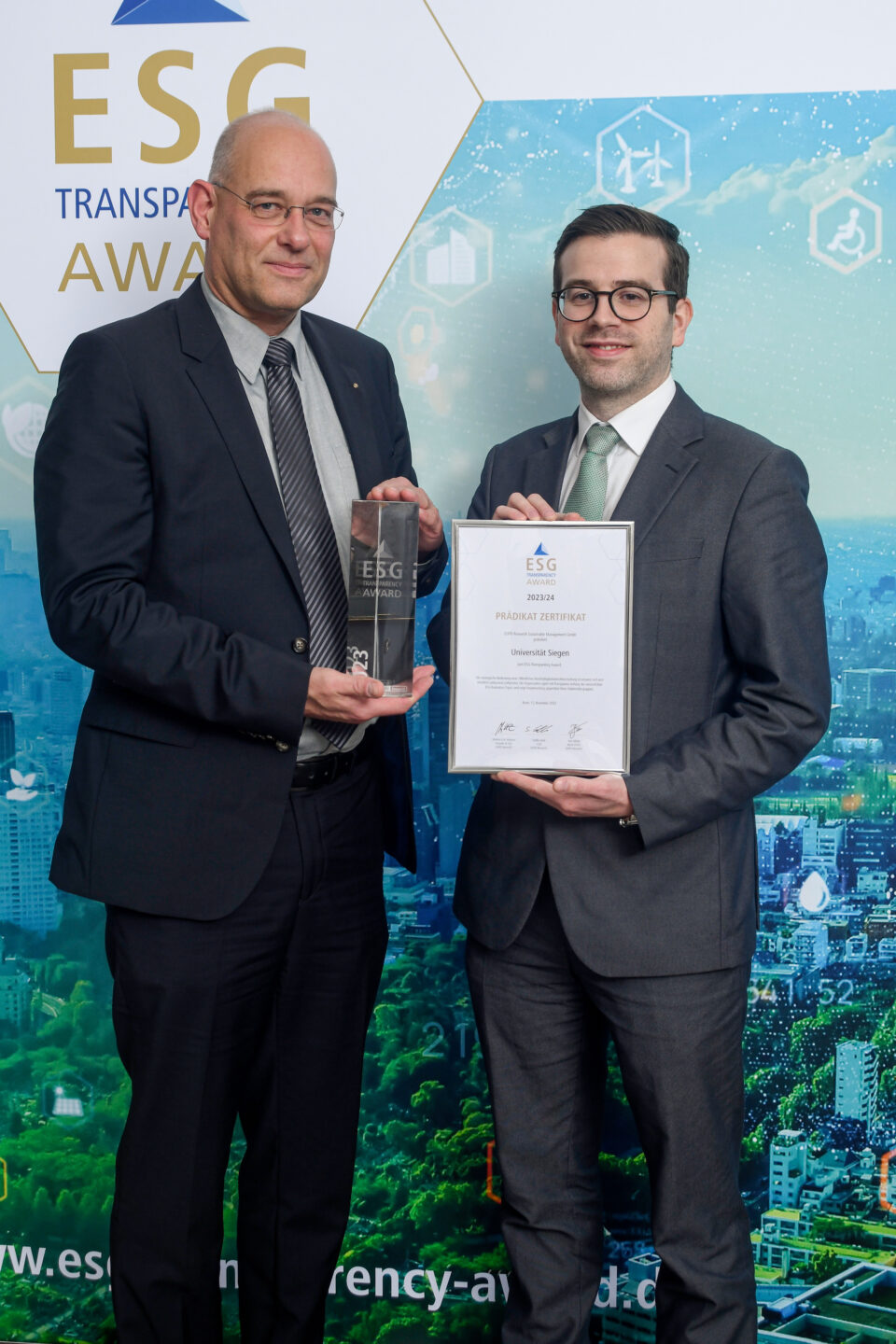 Zwei Männer in Anzügen halten vor einer ESG Transparency Award-Werbewand eine Trophäe und eine Urkunde