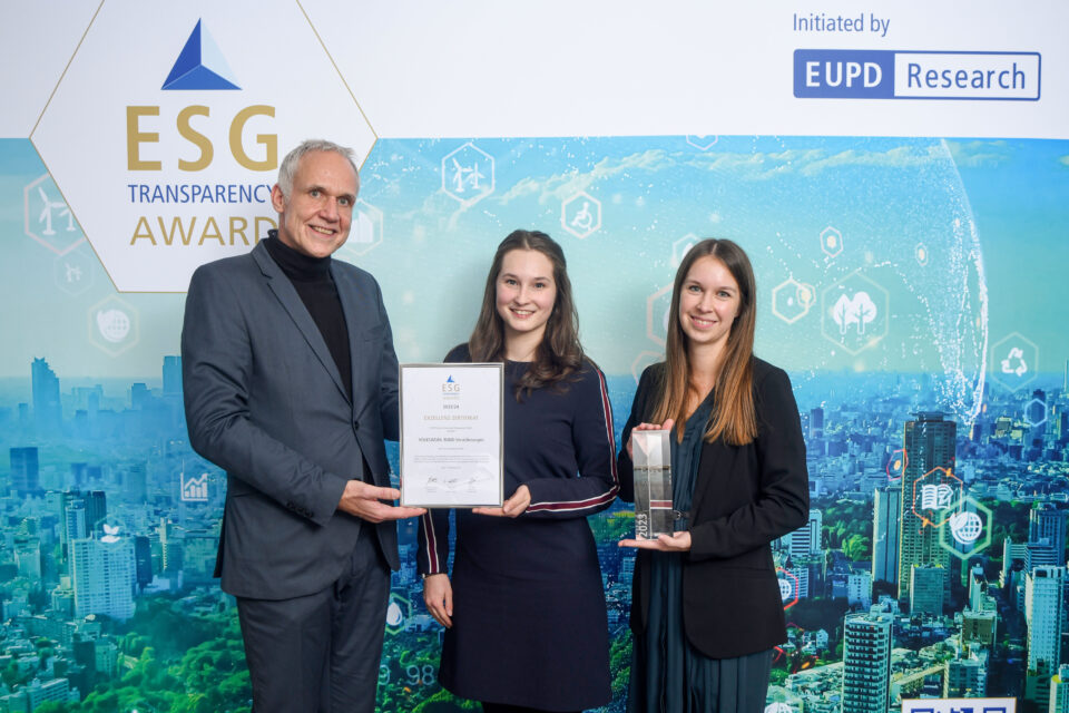 Drei Personen stehen vor einer Wand mit dem Schriftzug 'ESG Transparency Award' und 'EUPD Research', eine Person hält eine Urkunde, eine andere eine Trophäe